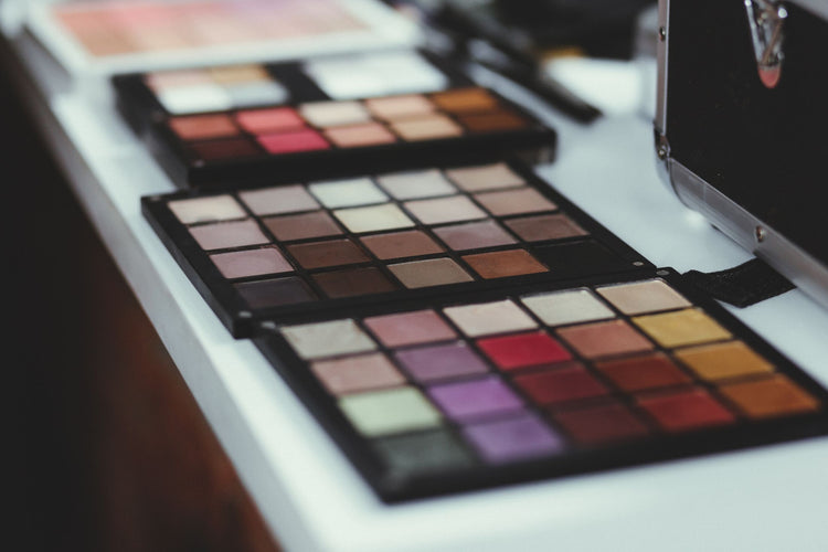 Close-up of vibrant makeup palettes laid out on a modern white table indoors.