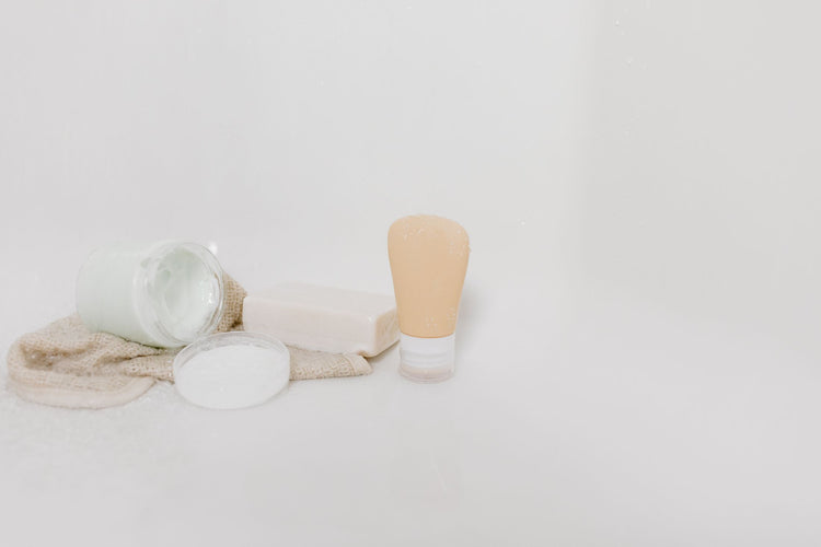 Minimalist setup of skincare products including cream, soap, and lotion on a white surface for beauty and self-care them