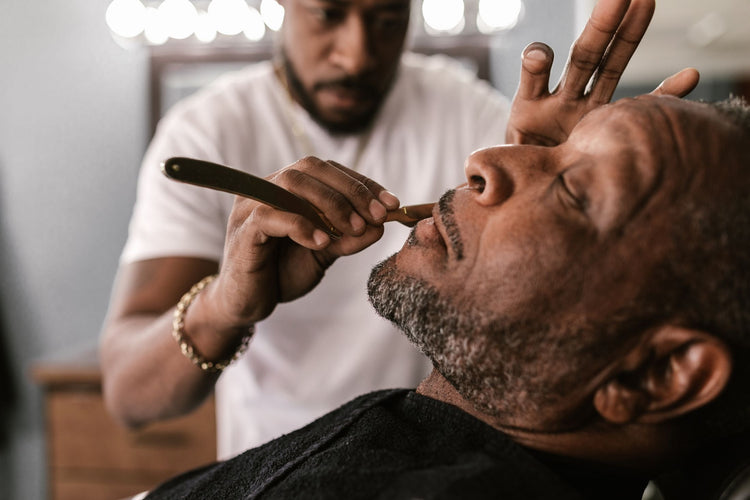 Close-up of a barber using a straight razor for precise grooming.